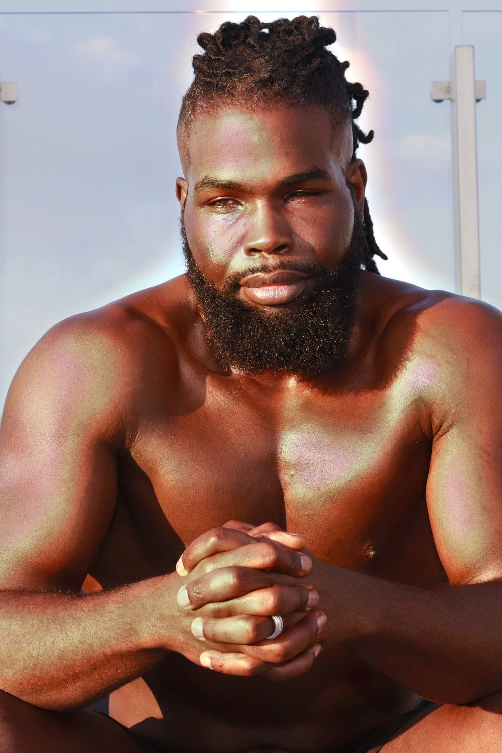 A warm close portrait, hands clasped, beard, a calm and direct gaze.