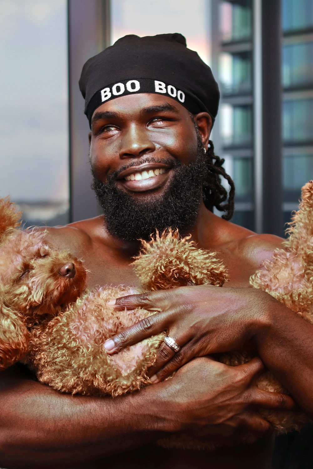 Beaming in a 'Boo Boo' beanie, holding his dog close against his chest.