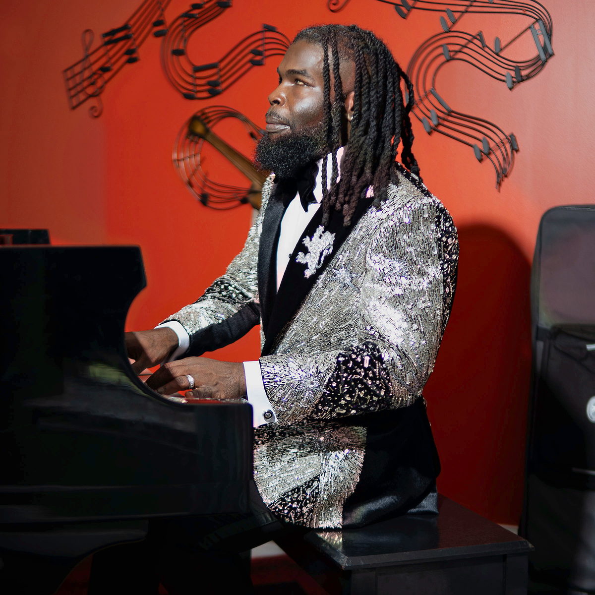 At a grand piano in a silver sequin jacket, in profile, music notes scrolling behind.